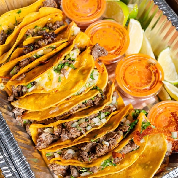 Big Papi's beef tacos with cilantro, onions, lime wedges, and salsa in a foil tray.
