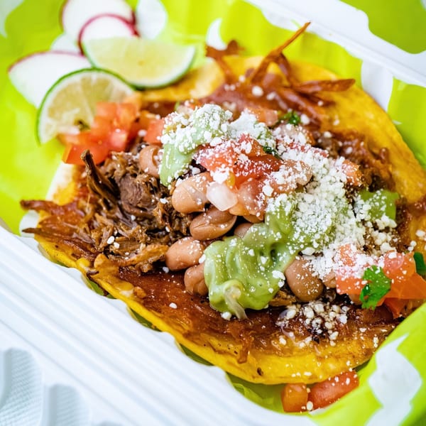 Close-up of a Big Papi's Mexican taco with meat, beans, guacamole, cheese, and lime.